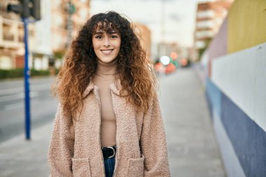 Genç İspanyol kadın gülümseyerek şehirde mutlu mesut dikiliyor.