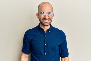 Gündelik kıyafetler ve gözlük takan genç İspanyol adam pozitif ve mutlu görünüyor ve kendine güvenen bir gülümsemeyle dişlerini gösteriyor. 