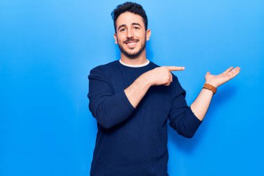 Gündelik kıyafetler giyen genç İspanyol adam kameraya hayret ediyor ve gülümsüyor.. 