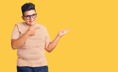 Küçük çocuk gündelik giysiler ve gözlük takıyor kameraya hayret ediyor ve gülümsüyor.. 