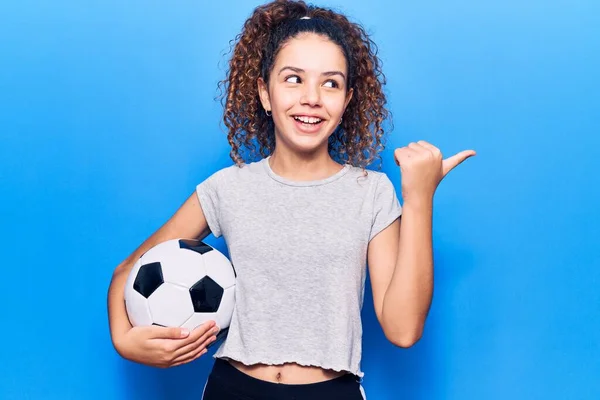 Hermosa Niña Con Pelo Rizado Sosteniendo Pelota Fútbol Apuntando Pulgar —  Fotos de Stock