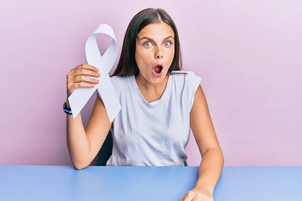 Young Caucasian Woman Holding White Ribbon Scared Amazed Open Mouth — Stock Photo, Image
