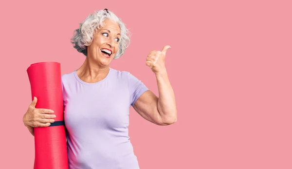 Senior Grey Haired Woman Holding Yoga Mat Pointing Thumb Side — Stock Photo, Image