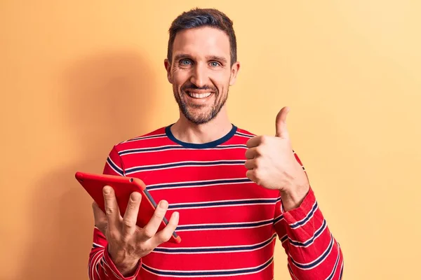 Joven Hombre Guapo Sosteniendo Touchpad Pie Sobre Fondo Amarillo Aislado —  Fotos de Stock