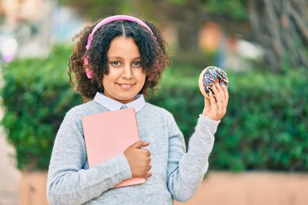 Bedårande Hispanic Student Flicka Hålla Bok Och Äta Munk Parken — Stockfoto