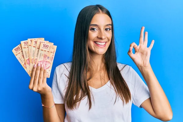 Young Hispanic Woman Holding Mexican Pesos Doing Sign Fingers Smiling — Stock Photo, Image