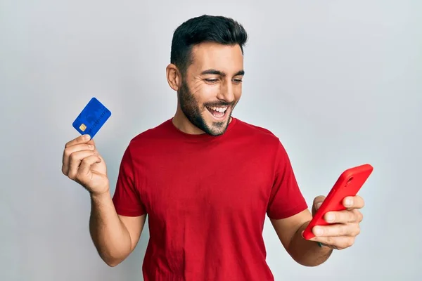 Νεαρός Ισπανόφωνος Κρατώντας Smartphone Και Πιστωτική Κάρτα Χαμογελώντας Και Γελώντας — Φωτογραφία Αρχείου