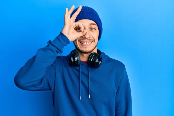 Latynoski Młody Człowiek Bluzie Słuchawkach Robi Gest Ręką Uśmiechniętą Oko — Zdjęcie stockowe