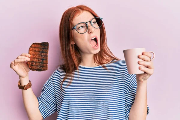 Young Red Head Girl Holding Burned Toast Breakfast Angry Mad — Zdjęcie stockowe