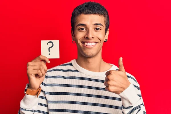 疑問符を保持している若いアフリカ系アメリカ人男性は笑顔と正を思い出させます 親指アップ素晴らしいと承認サインを行う — ストック写真