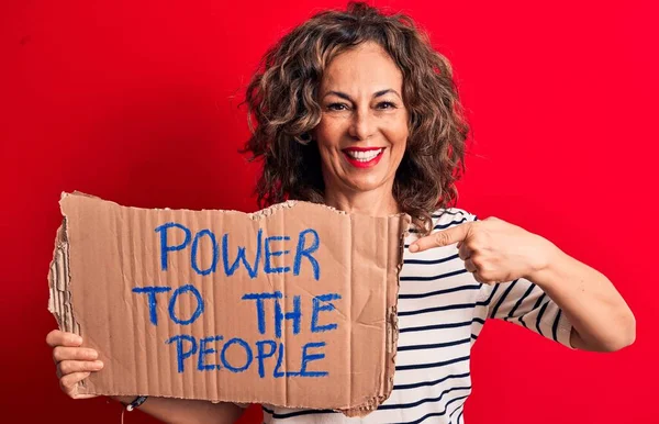 Senior woman asking for social movement holding banner with power to the people message smiling happy pointing with hand and finger