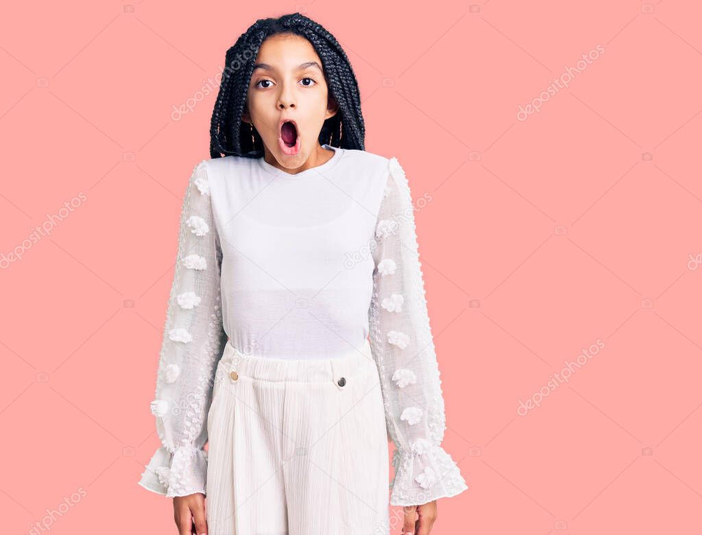 Cute african american girl wearing casual white tshirt afraid and shocked with surprise expression, fear and excited face. 