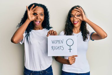 Afrika kökenli Amerikalı anne ve kız ellerinde kadın hakları afişi mutlu mesut gülümsüyorlar. El ele imzala ve parmaklarının arasından bak. 