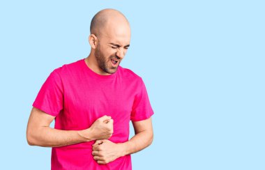 Mide bulantısı, acı verici bir hastalık yüzünden eli karnında sıradan tişörtler giyen genç yakışıklı bir adam. Ağrı kavramı. 