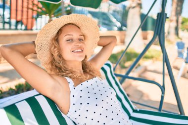 Sarışın, güzel, beyaz bir kadın. Gülümsüyor. Mutlu bir yaz günü açık havada rahatlıyor.