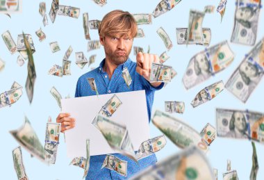 Sakallı yakışıklı, beyaz bir adam elinde fotoğraf makinesini işaret eden bir poster taşıyor. Kendine güveni tam bir jest gibi duruyor.