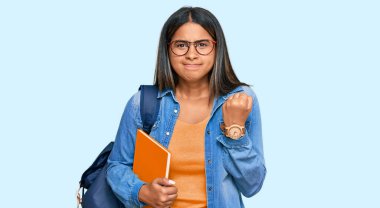 Öğrenci sırt çantası takan, elinde kızgın ve kızgın kitaplar tutan öfkeli, sinirli ve öfkeliyken öfkeyle bağıran Latin kız. öfke ve agresif konsept. 