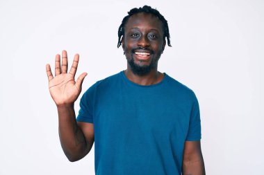 Saçları örgülü genç Afro-Amerikalı adam beş numarayı gösterip gösterirken kendinden emin ve mutlu gülümsüyor.. 