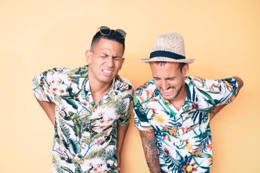 İki genç eşcinsel adam yaz şapkası takıyor ve Hawaii gömleği giyiyor sırt ağrısı çekiyor, elleriyle dokunuyor, kas ağrısı çekiyor. 