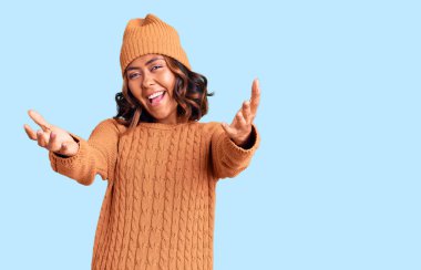 Genç, güzel, melez bir kadın yün kazak ve kış şapkası giyiyor. Gülümsüyor, yardım eli uzatıyor ve kabul ediyor.. 