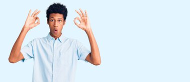 Gündelik giysiler giymiş genç Afro-Amerikan bir adam parmaklarıyla onay sembolü yaparken şaşırmış ve şok olmuş görünüyor. çılgın ifade 