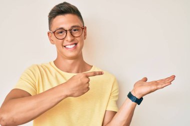 Günlük kıyafetler ve gözlük takan genç İspanyol çocuk kameraya hayret ediyor ve gülümsüyor.. 