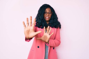 İş ceketi ve gözlük takan güzel Afrikalı kadın korku ifadesinden korkmuş ve dehşete düşmüş. El kol hareketi yapmayı kes, şok içinde bağır. panik konsepti. 