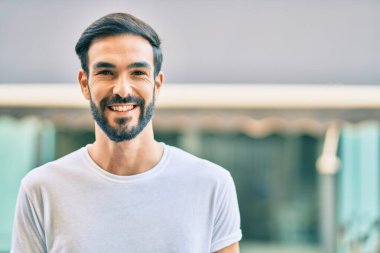 Genç İspanyol adam gülümseyerek şehirde mutlu mesut dikiliyor..