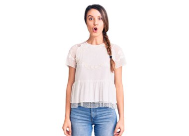Gündelik tişört giyen genç ve güzel bir kız. Korkmuş ve ağzı açık kalmış, şaşırmış ve şaşırmış. 