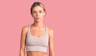 Güzel beyaz kadın spor giysisi giyiyor ve yüzünde ciddi bir ifadeyle rahatlıyor. Basit ve doğal bir şekilde kameraya bakıyorsun.. 