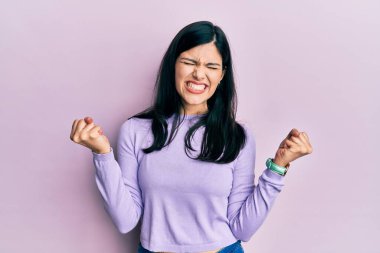 Genç İspanyol kadın gündelik kıyafetler giyiyor çok mutlu ve heyecanlı kazanan jestler yapıyor kolları havada, gülümsüyor ve başarı için bağırıyor. kutlama konsepti. 