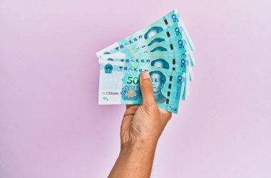 İspanyol el, 50 Yuan 'lık Çin banknotunu soyutlanmış pembe arka planda tutuyor..