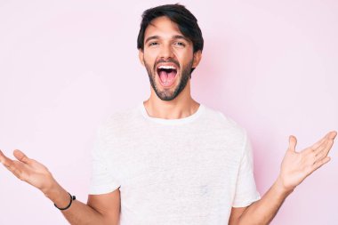 Yakışıklı, beyaz tişörtlü, mutlu bir gülümsemeyle zaferi kutlayan ve ellerini kaldırarak kazanan bir İspanyol. 