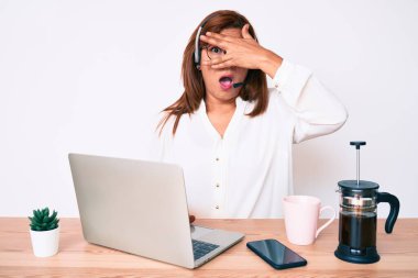 Orta yaşlı esmer, ofiste çalışan, operatör kulaklığı takan, yüzü ve gözleri elleriyle kapatan, parmaklarından korkan İspanyol bir kadın. 