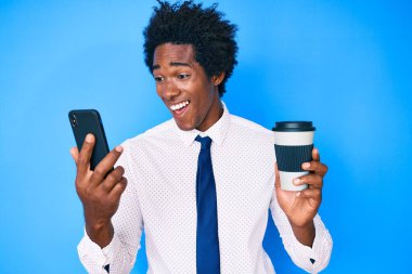Afro saçlı, akıllı telefon kullanan, bir fincan kahve içen ve kahkahalarla kahkahalarla gülen yakışıklı Afro-Amerikan bir adam.. 