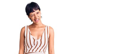 Kısa saçlı, kısa saçlı, yaz kıyafetli genç bir kadın kameraya seksi bir ifadeyle bakıyor, neşeli ve mutlu bir yüzü var.. 