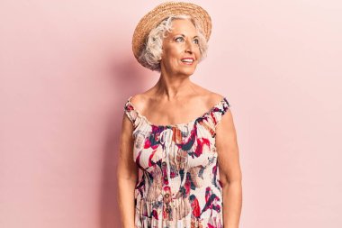Beyaz saçlı, yaz şapkası takan, rahat bir görünüm takınan, doğal yüzlü, kendine güvenen bir gülümseme takınan yaşlı kadın.. 