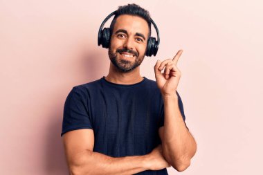 Genç İspanyol adam, kulaklık takıp müzik dinliyor. Gülümsüyor, mutlu bir şekilde işaret ediyor. 