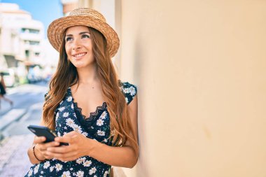 Genç İspanyol kadın şehir caddesinde akıllı telefon kullanıyor..