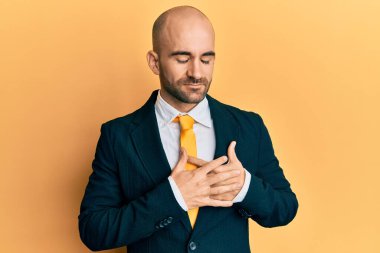 Genç İspanyol bir adam iş elbisesi ve kravat takıyor elleri göğsünde, gözleri kapalı gülümsüyor ve yüzünde minnet ifadesi var. sağlık kavramı. 