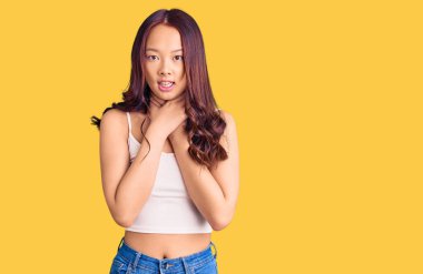 Genç ve güzel Çinli kız günlük kıyafetler giyip bağırıyor ve boğuluyor çünkü acı verici bir şekilde boğulmuş. Sağlık problemi. Boğulma ve intihar konsepti. 