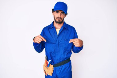 Kıvırcık saçlı ve ayı gibi giyinen yakışıklı genç adam üzgün ve üzgün görünüyor, parmaklarıyla yönü gösteriyor, mutsuz ve depresif.. 