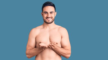 Mayo giyen, elleri avuçlarında gülümseyen genç yakışıklı adam el hareketi yapıyor. Bekleme ve koruma 