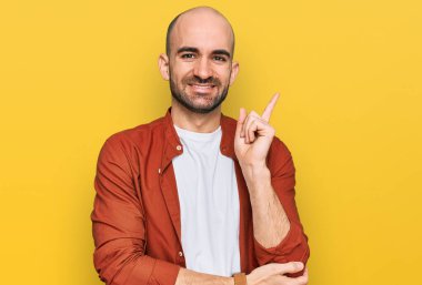 Yüzünde kocaman bir gülümseme olan, gündelik kıyafetler giyen genç İspanyol adam, kameraya el ve parmak ile bakıyor.. 