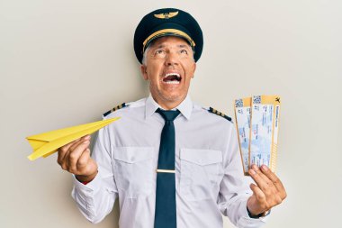 Yakışıklı, orta yaşlı, elinde kağıt uçak ve biniş kartı olan olgun bir pilot. Kızgın ve kızgın çığlıklar atıyor. Öfkeyle bağırıyor.. 