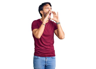 Yakışıklı İspanyol bir adam günlük kıyafetler giyiyor ve elleri ağzında bağırıyor. 