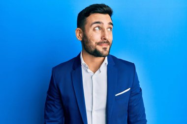 Genç İspanyol iş adamı iş ceketi giyiyor. Gülümsüyor, yan tarafa bakıyor ve düşünüyor.. 