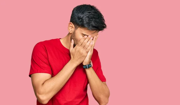 泣きながら手で顔を覆う悲しい表情のカジュアルな赤いTシャツを着た若いハンサムな男 うつ病の概念 — ストック写真