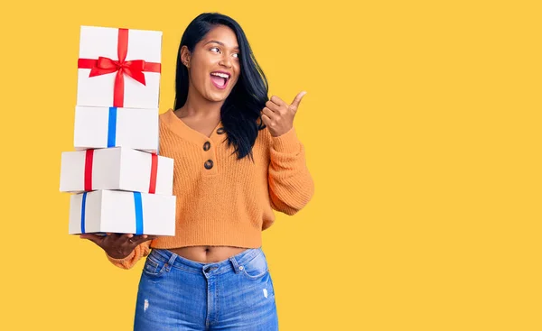 Mujer Hispana Con Cabello Largo Sosteniendo Regalos Apuntando Con Pulgar — Foto de Stock