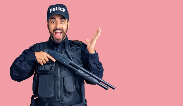 Young Hispanic Man Wearing Police Uniform Holding Shotgun Celebrating Victory — Stock Photo, Image